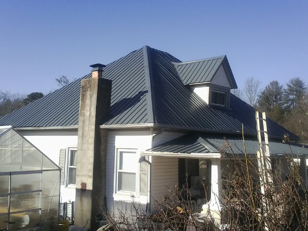 Dark blue standing seam metal roof on a white farmhouse with dormer — Slate & Tile Roof Repair by Roofing Brothers in Frederick