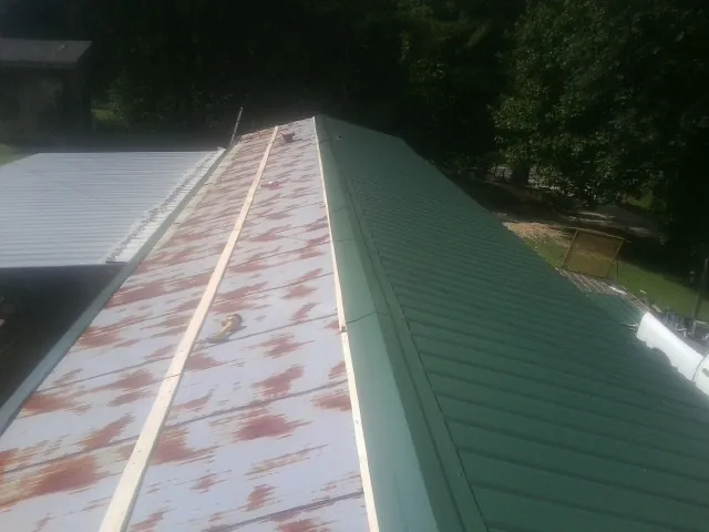 Old rusted panels beside newly installed green metal roofing — Wind Damage Roof Repair by Roofing Brothers in Frederick